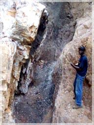 Rockson Coffie PGeo mapping structure where locals heat the quartz veins with fire and splash with water to break the rock for extracting gold.